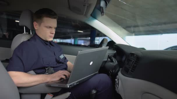 Un policier travaille sur un ordinateur portable dans une voiture de patrouille, surveille la carte des incidents, la technologie — Video