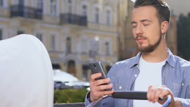 Excited man with baby stroller holding smartphone, shopping online, web surfing — Stock Video