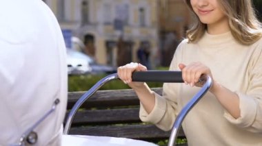 Mutlu anne sallanan bebek arabası, parkta boş zaman, yeni doğan çocuk bakımı