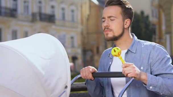 Gelukkige jonge vader schudden baby speelgoed en swingende wandelwagen, pasgeboren kind zorg — Stockvideo