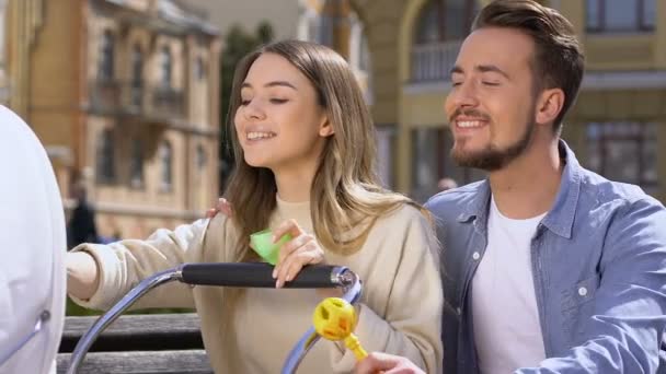 Keluarga bahagia makan bayi di kereta dari botol susu dan bermain dengan mainan — Stok Video