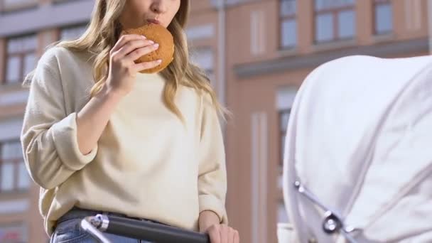 Vrouw die Fast Food eet, een wandeling met baby, jonge moeders dieet concept, gezondheidszorg — Stockvideo