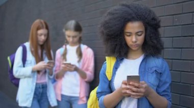 Kız okul öğrencileri açık havada akıllı telefonlar kaydırma, gadget bağımlılığı, internet