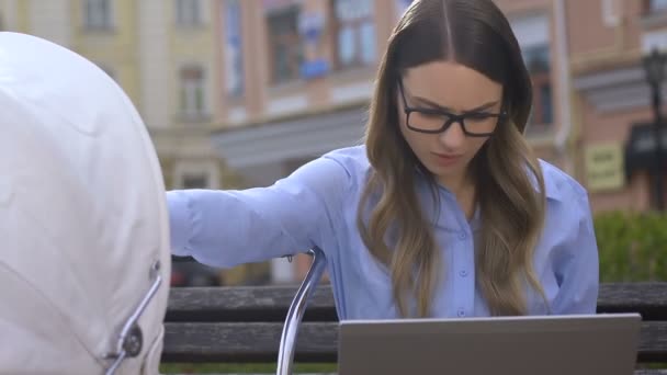 Busy woman feeding baby while working on laptop, difficult life of single mother — Stock Video