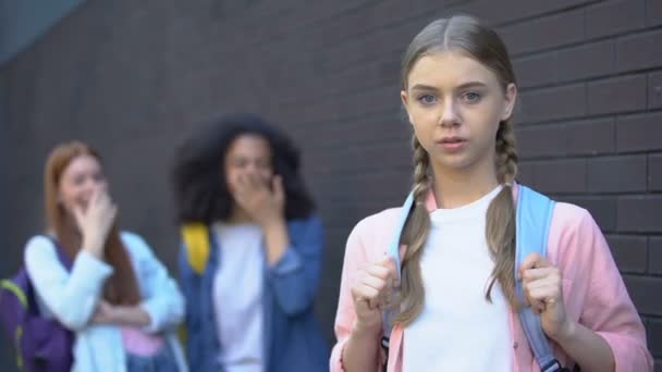 Confuso vítima de bullying olhando câmera, estudantes do sexo feminino rindo atrás, estresse — Vídeo de Stock