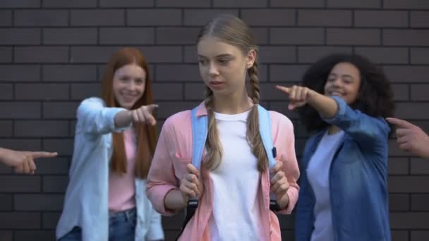 Жіночі підлітки вказують пальці відчайдушної школярки, коледж дражнить засудження — стокове відео
