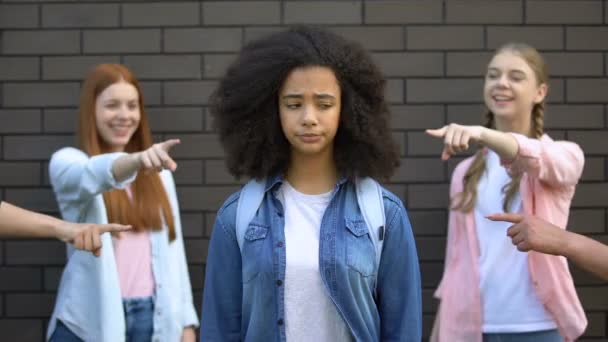 Жестокая группа подростков, указывающая пальцем на кудрявую афро-американскую школьницу, расизм — стоковое видео
