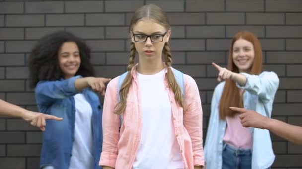 Gruppe Gleichaltriger zeigt mit dem Finger auf neue intelligente College-Studentin, Verurteilung — Stockvideo