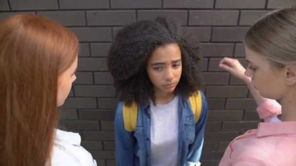 Two caucasian schoolgirls intimidating afro-american classmate, teen cruelty — Stock Video