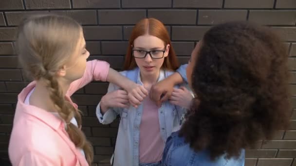 Étudiants arrogants poussant avec coude adolescent féminin contre le mur de l'école arrière-cour — Video