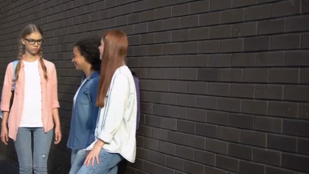 Two female students teasing passing schoolgirl in eyeglasses, condemnation — Stock Video