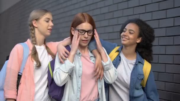 Students offending smart classmate in eyeglasses putting hands on shoulders — Stock Video