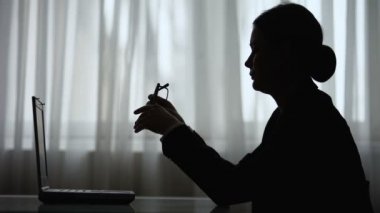 Gözlük takmak ve dizüstü bilgisayarda yazmaya başlayan yorgun kadının gölgesi, son tarih