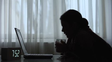 Uykusuz kadın sabah dizüstü bilgisayar üzerinde çalışan çay içme, iş sorumlulukları