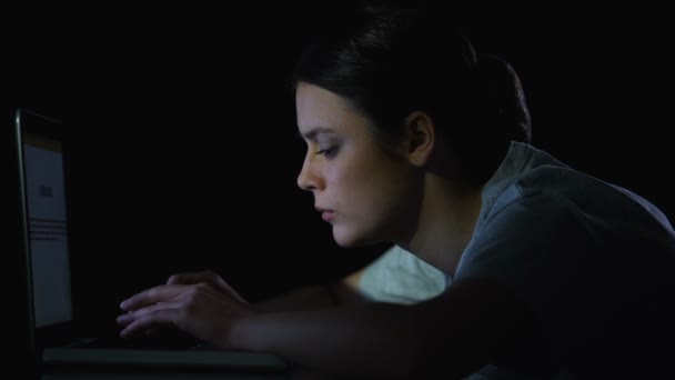 Étudiante tapant sur ordinateur portable tard le soir, travaillant sur un projet de diplôme 