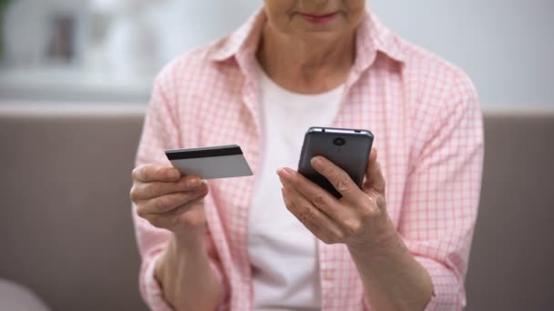 Senior feminino inserir número de cartão de crédito no smartphone, pagar contas on-line — Vídeo de Stock