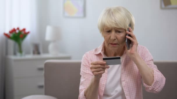 Confused aged woman with credit card calling bank support, payment problems — Stock Video