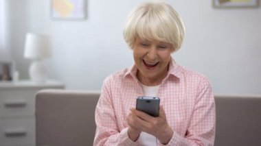 Son derece memnun üst düzey kadın akıllı telefon, sosyal ağ üzerinde fotoğraf kaydırma