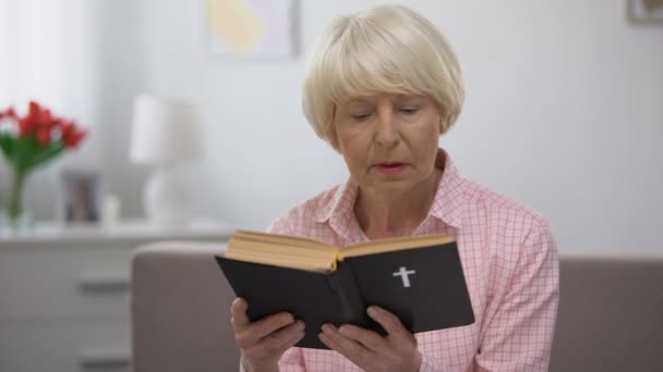 Релігійна старша жінка читає святу Біблію вдома, концепцію віри та віри — стокове відео