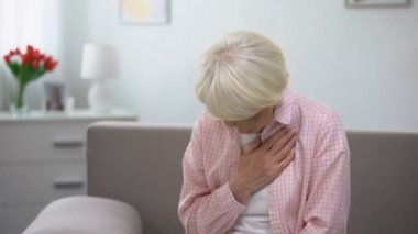 Yaşlı kadın göğüs üzerinde el tutarak, kalp ağrısı, sağlık sorunları muzdarip