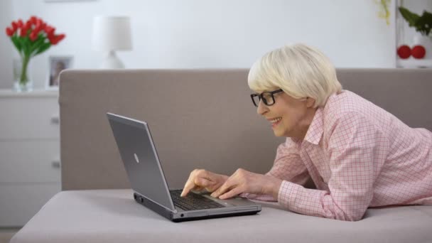 Mujer anciana sonriente charlando en el portátil con la familia, estudiando las redes sociales — Vídeos de Stock