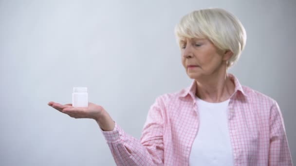 Femme âgée mécontente tenant une bouteille de pilules, médecine méfiante, traitement — Video