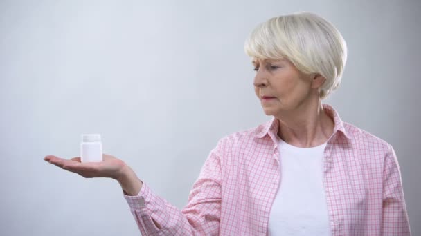 Ταραγμένη γριά κυρία κρατώντας μπουκάλι χάπια, αναποτελεσματική θεραπεία, κακής ποιότητας ιατρική — Αρχείο Βίντεο
