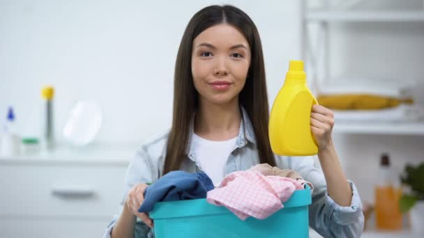 Dona de casa com cesta cheia de roupas e detergente de lavanderia mostrando polegares para cima — Vídeo de Stock