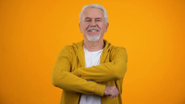 Lachende oudere man met gevouwen armen winking op camera, zelfvertrouwen, flirt — Stockvideo