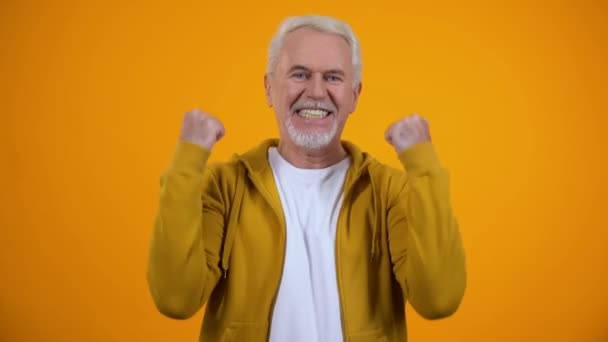 Veselý mužský důchodce s úspěšným gestem a s úsměvem na spokojenosti fotoaparátu — Stock video