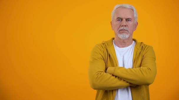 Senior berührt Kinn und denkt über Entscheidung vor orangefarbenem Hintergrund nach — Stockvideo