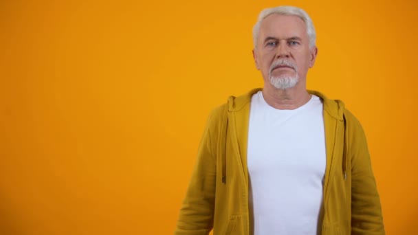 Hombre en sus 50 años conmocionado con noticias inesperadas contra fondo naranja, confusión — Vídeo de stock
