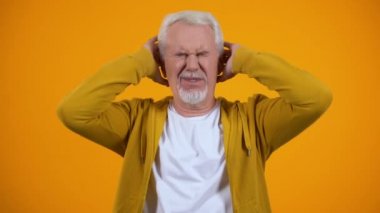Emekli erkek avuç içi ile kulakları kapsayan turuncu arka plan üzerinde dedikodular ile hoşnutsuz