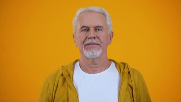 楽観的な先輩男性がオレンジ色の背景、幸せに対して心から笑う — ストック動画