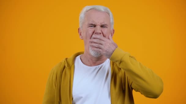 Hombre de edad soñoliento bostezando en la cámara contra fondo naranja, problema de insomnio — Vídeo de stock