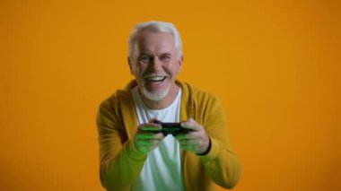 Joystick videooyunu oynarken mutlu emekli, yuvarlak sonuç, zafer ile mutlu