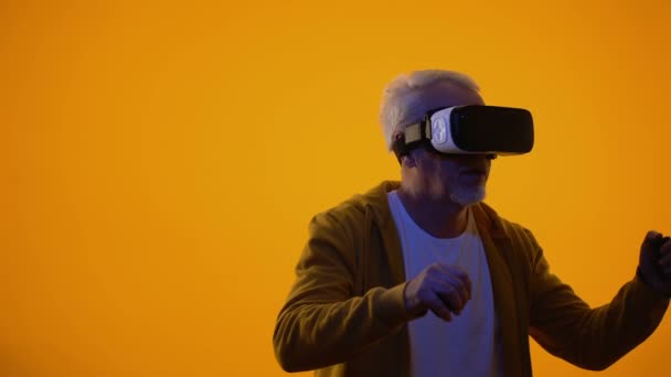 Мужчина-пенсионер в очках виртуальной реальности, играющий в видеоигры, современные технологии — стоковое видео