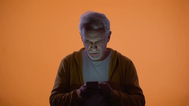 Oude man lijdt slecht zicht probeert te typen bericht op smartphone gezondheidsprobleem — Stockvideo