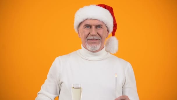 Šťastný starší muž v Santa Clause s Bengálským světlem ukazující sklo šampaňského — Stock video