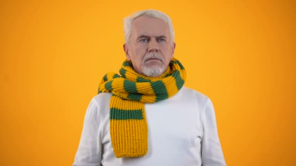 Enfermo anciano en bufanda tos contra fondo naranja, síntoma de bronquitis — Vídeos de Stock