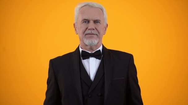 Lächelnder alter Mann im Anzug präsentiert Tulpenstrauß und Geschenkbox, herzlicher Gruß — Stockvideo