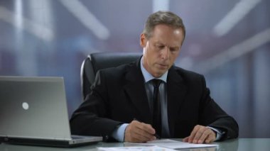 Ciddi işadamı okuma ve ofis masasında önemli sözleşmeler imzalama