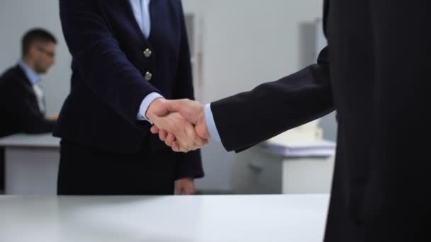 Uomo e donna in giacca e cravatta che si stringono la mano sul posto di lavoro, affari, cooperazione — Video Stock