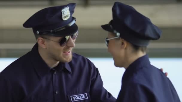 Politieagenten in zonnebrillen praten en lachen, partners patrouilleren samen — Stockvideo