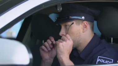Arabada güneş gözlüğü takan üniformalı saygıdeğer polis memuru, devriye