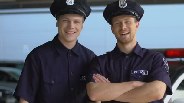 Dos compañeros en uniforme de policía y gorra sonriendo, mirando a la cámara, aprendices — Vídeo de stock