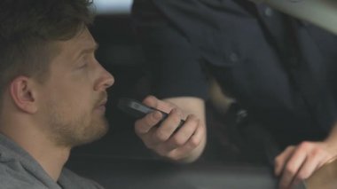 Polis alkol içeriğini kontrol etmek için nefes örneği veren sinirli adam, yol güvenliği