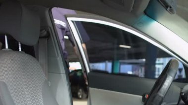 Ciddi polis arabaya biniyor, güneş gözlüğü takıyor ve araba motoru çalıştırıyor, görev