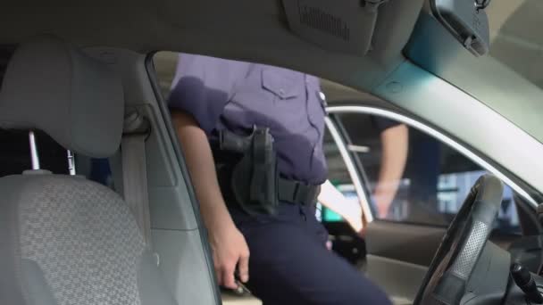 Храбрый полицейский садится в машину в солнечных очках, патрулирует город — стоковое видео