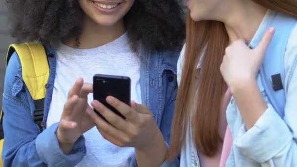 Девочки-подростки смеются над сообщениями в социальных сетях о одноклассниках, кибериздевательствах — стоковое видео